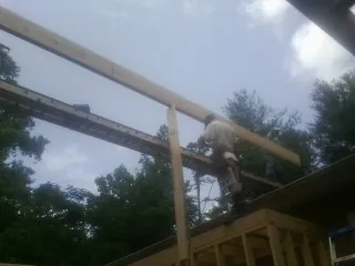 Carpenter setting a ridge beam over a new addition frame — Ice Dam Removal by Roofing Brothers in Mount Saint Joseph