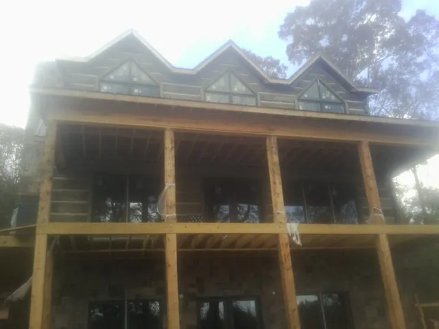 Dormers and porch framing on a large log home under construction — Roof Coating work by our crew in Mount Saint Joseph