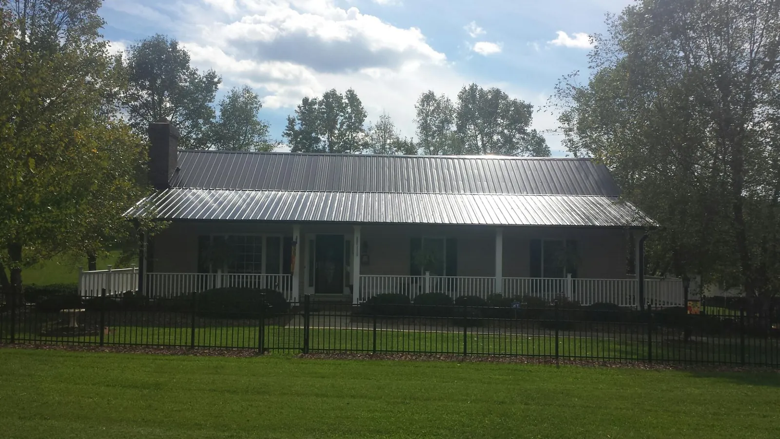 Gray metal roof on a brick ranch with a full width front porch — Gutter Guard Installation work by our crew in Mount Saint Joseph