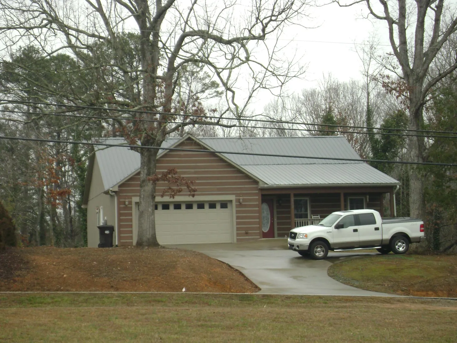 Gray metal roof on a log sided house with an attached two car garage in Mount Saint Joseph