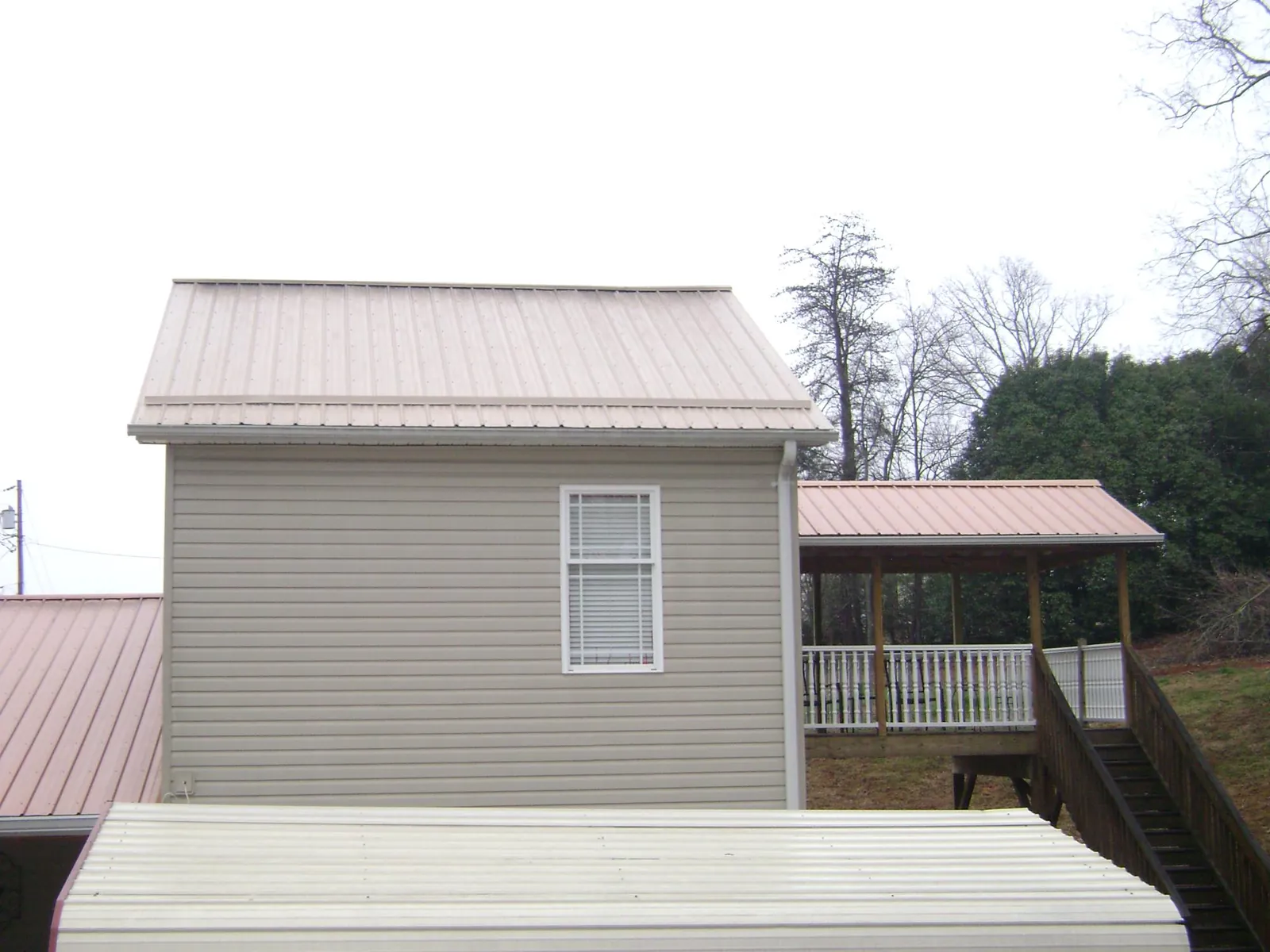 Tan metal roofs on a two story addition and attached porch, from a Roof Replacement job in Mount Saint Joseph