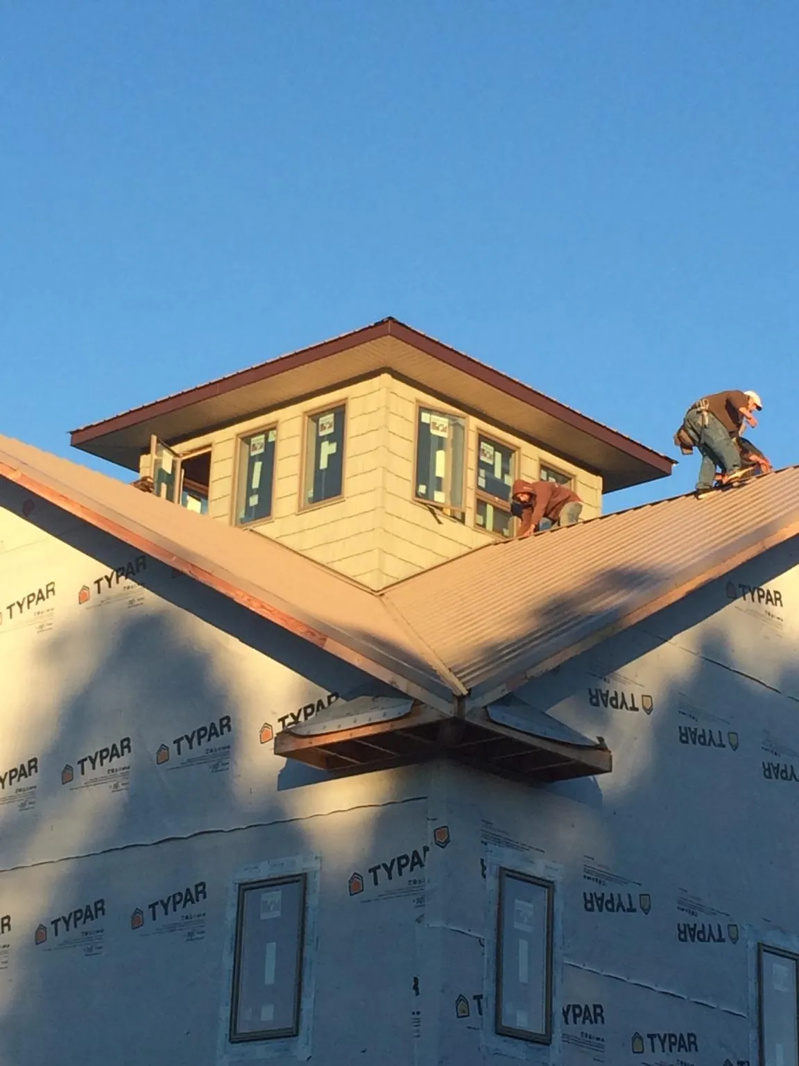 Roofers working around a rooftop cupola on a new metal roof at sunset — Roof Waterproofing in Mount Saint Joseph by Roofing Brothers